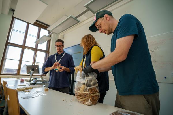 Workshop participants examining material inside a large transparent cultivation bag